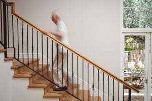Parkinson’s patient climbing stairs at home with a railing.